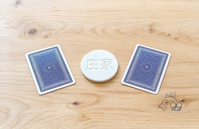 浅木桌面上一枚白色圆形庄家按钮与左右两张翻扣的牌背
